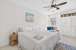 A bedroom with a bed, a ceiling fan, a painting, a window, and a wardrobe. - Beautiful condo located on the ship channel in the heart of Port Aransas! The ga (Port Aransas)