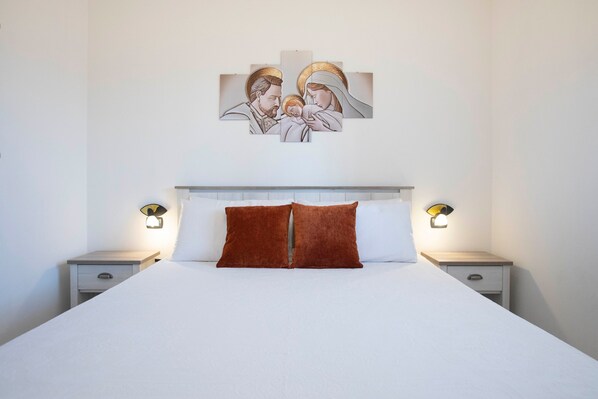 Ein Schlafzimmer mit einem großen Bett, zwei Nachttischen und einem an der Wand hängenden Kunstwerk.