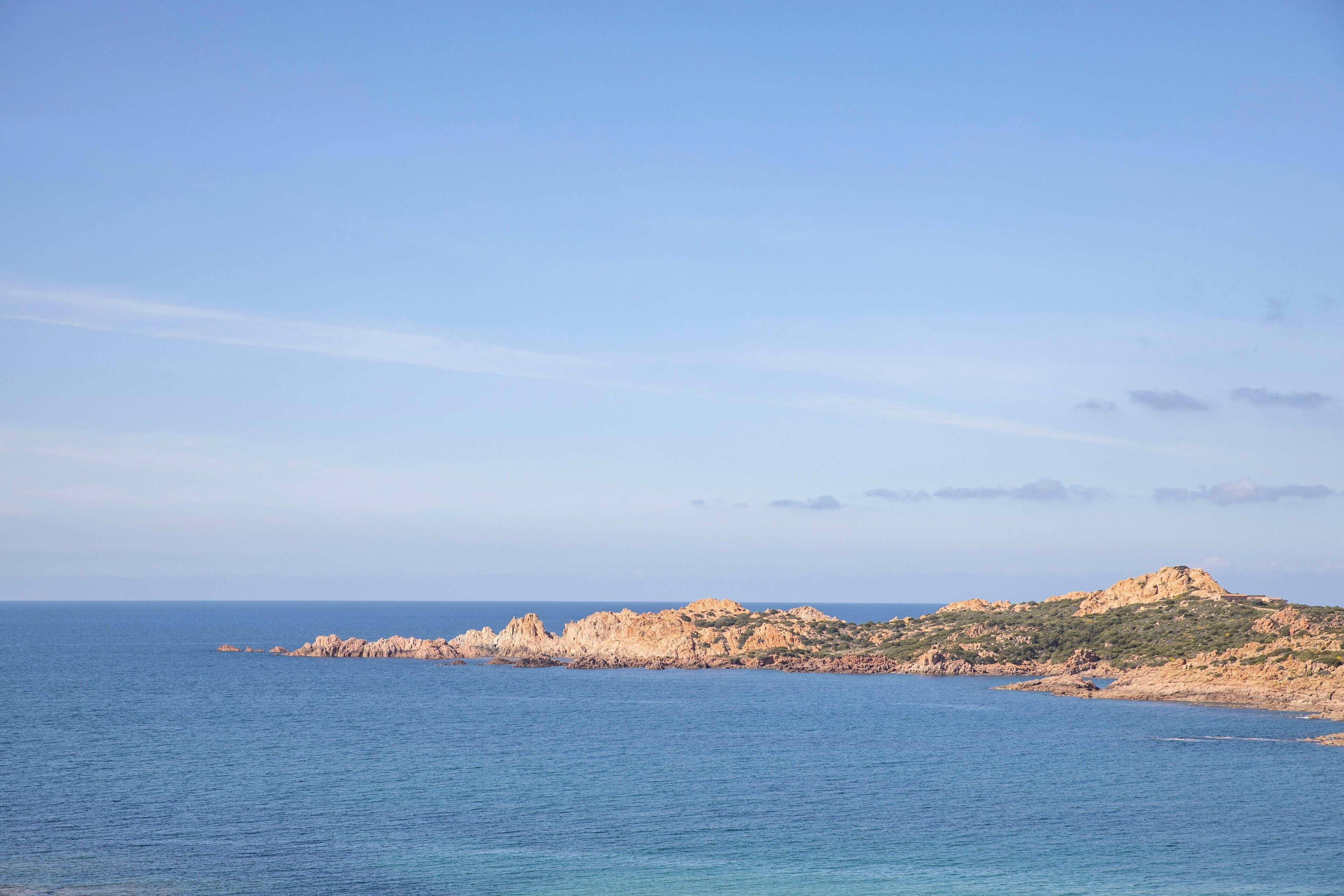 A coastal landscape with rocky terrain and calm sea.
