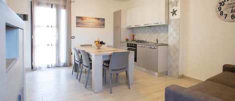 Cocina moderna con comedor, sofá y un reloj de pared.
