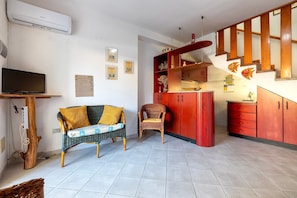 A living room with a television, a sofa, a chair, a red cabinet, and a staircase.