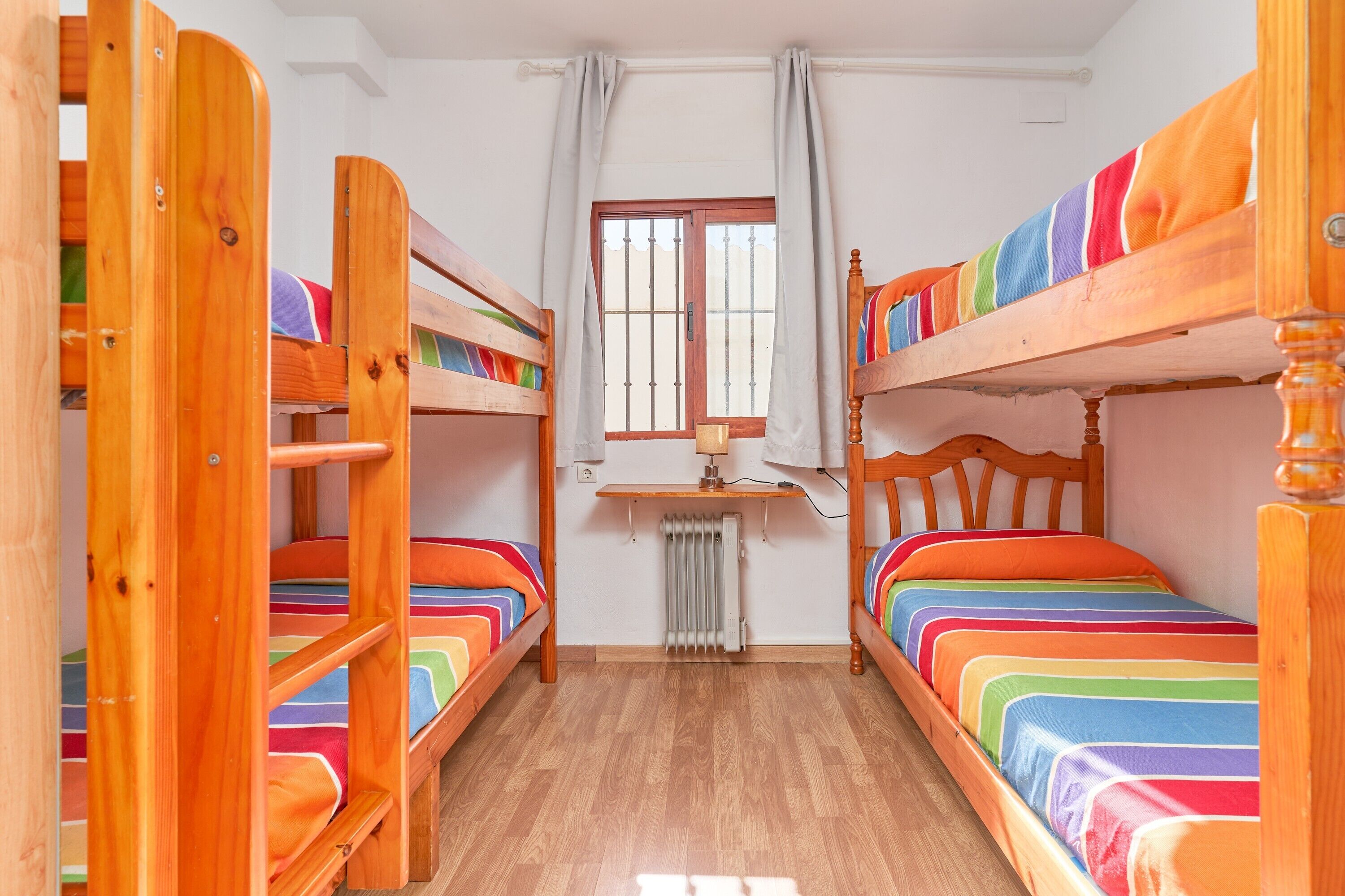A room with bunk beds, a desk, and a window with curtains.