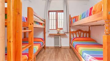 A room with bunk beds, a desk, and a window with curtains.