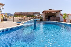 A swimming pool with a diving board, outdoor seating, and a bar area. - Holiday Home 'Cabrera' with Sea View, Private Pool and Wi-Fi (Puntalon)