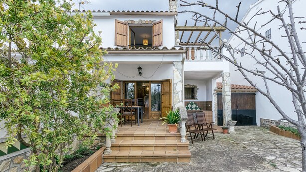 A two-story building with a stone-paved courtyard, wooden shutters, and a balcony. - Villa 'Olivera' with Private Terrace and Private Garden (L'Escala)