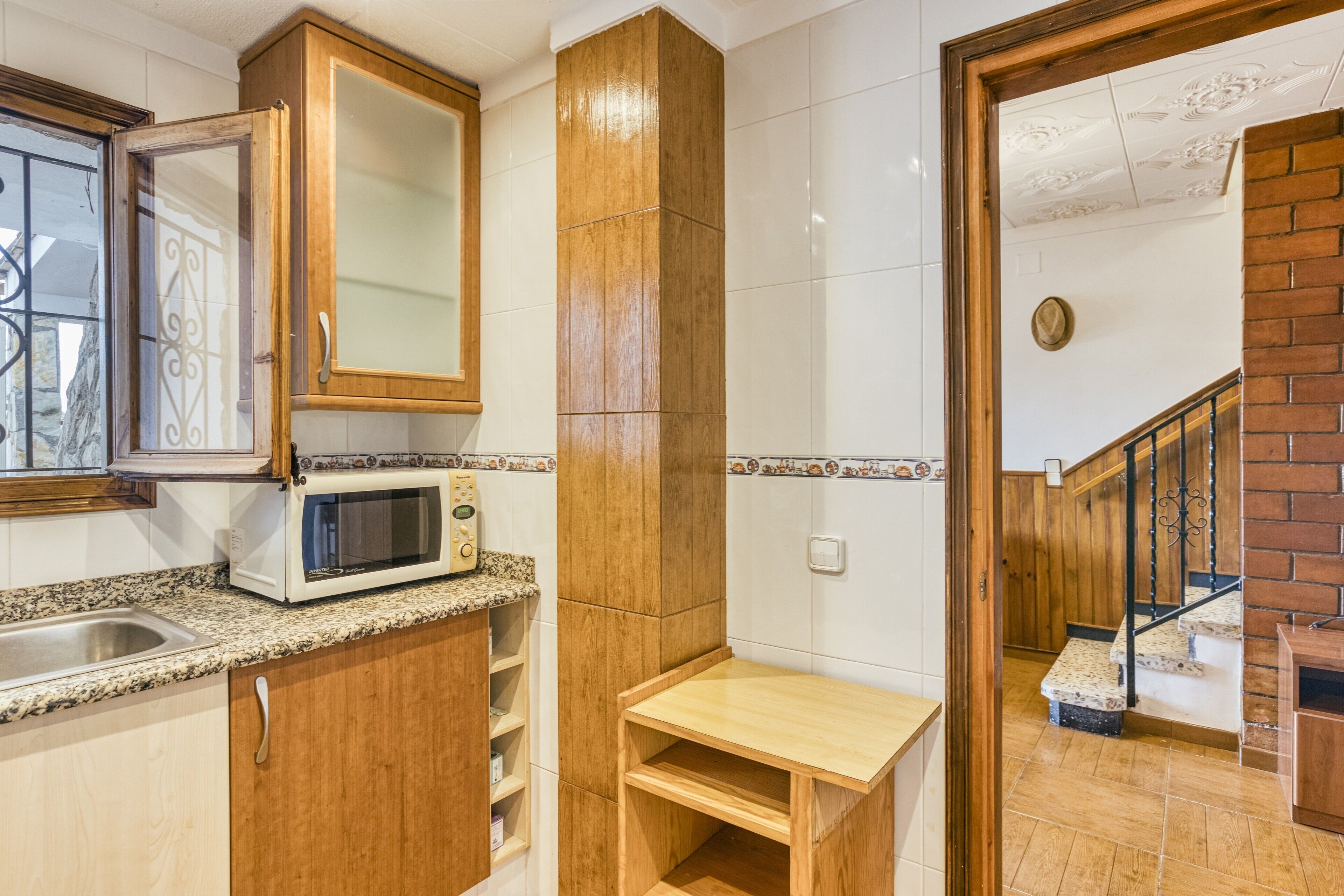 A kitchen with wooden cabinets, a microwave, and a small wooden table.