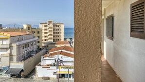 A balcony with a view of a coastal cityscape, including buildings and the sea.