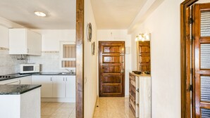 A kitchen with white cabinets, a microwave, and a wooden door.