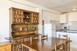 Un coin repas avec une table et des chaises en bois, une cuisine équipée d’un four à micro-ondes et d’une cuisinière, et un meuble orné de motifs décoratifs.