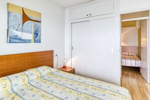 A bedroom with a bed, a nightstand, a wardrobe, and a painting on the wall. - Apartment 'Marinada' with Sea View, Shared Pool and Wi-Fi (l'escala)