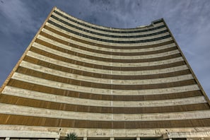 Een hoog, gebogen gebouw met meerdere horizontale verdiepingen en een reeks balkons.