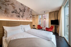 A hotel room with a bed, two red chairs, a TV, and a large window. - Villa Steiner 5 - Suzuka- Studio with balcony, air conditioning and wifi (Merano)