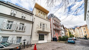Une rue pavée bordée d’immeubles, avec une voiture garée et un vélo.