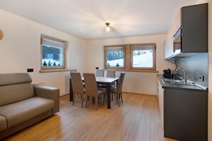 Un espacio habitable pequeño con sofá, mesa de comedor, sillas y kitchenette.