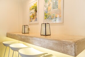 A reception area with a concrete counter, two framed artworks, and three white bar stools. - Villa "Armonia" with Sea View, Pool & Wi-Fi (Corfu)