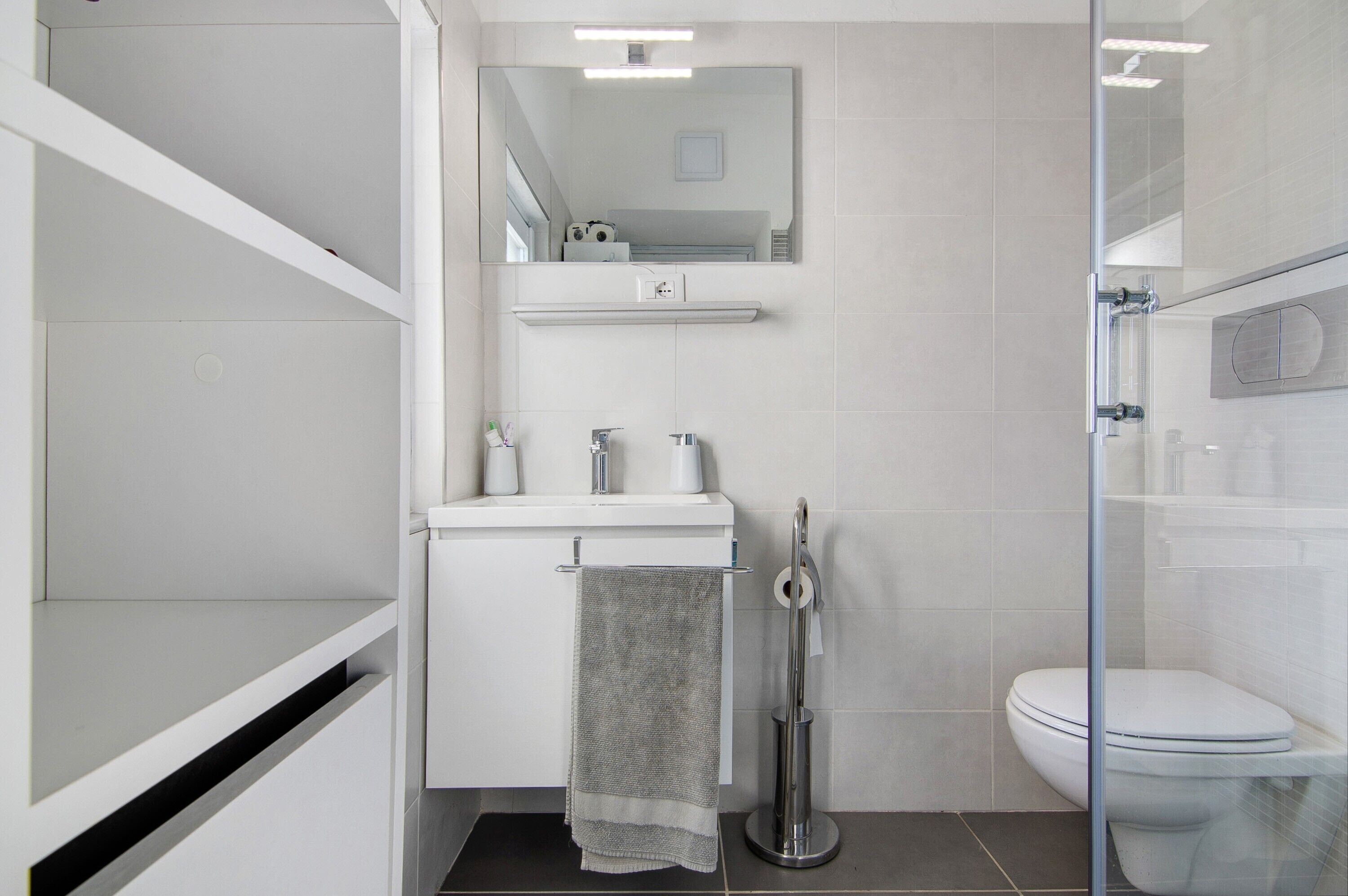 A modern bathroom with a glass shower enclosure, a white sink with a towel, and a toilet.