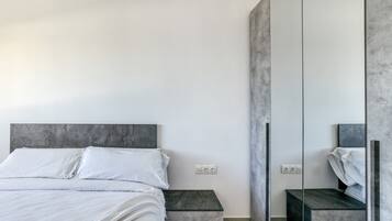 Un dormitorio moderno con cama, mesitas de noche, espejo y armario.