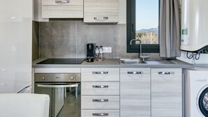 A modern kitchen with a built-in oven, a coffee maker, and a washing machine.