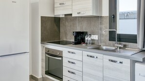A modern kitchen with a built-in oven, a coffee maker, and a stainless steel sink.