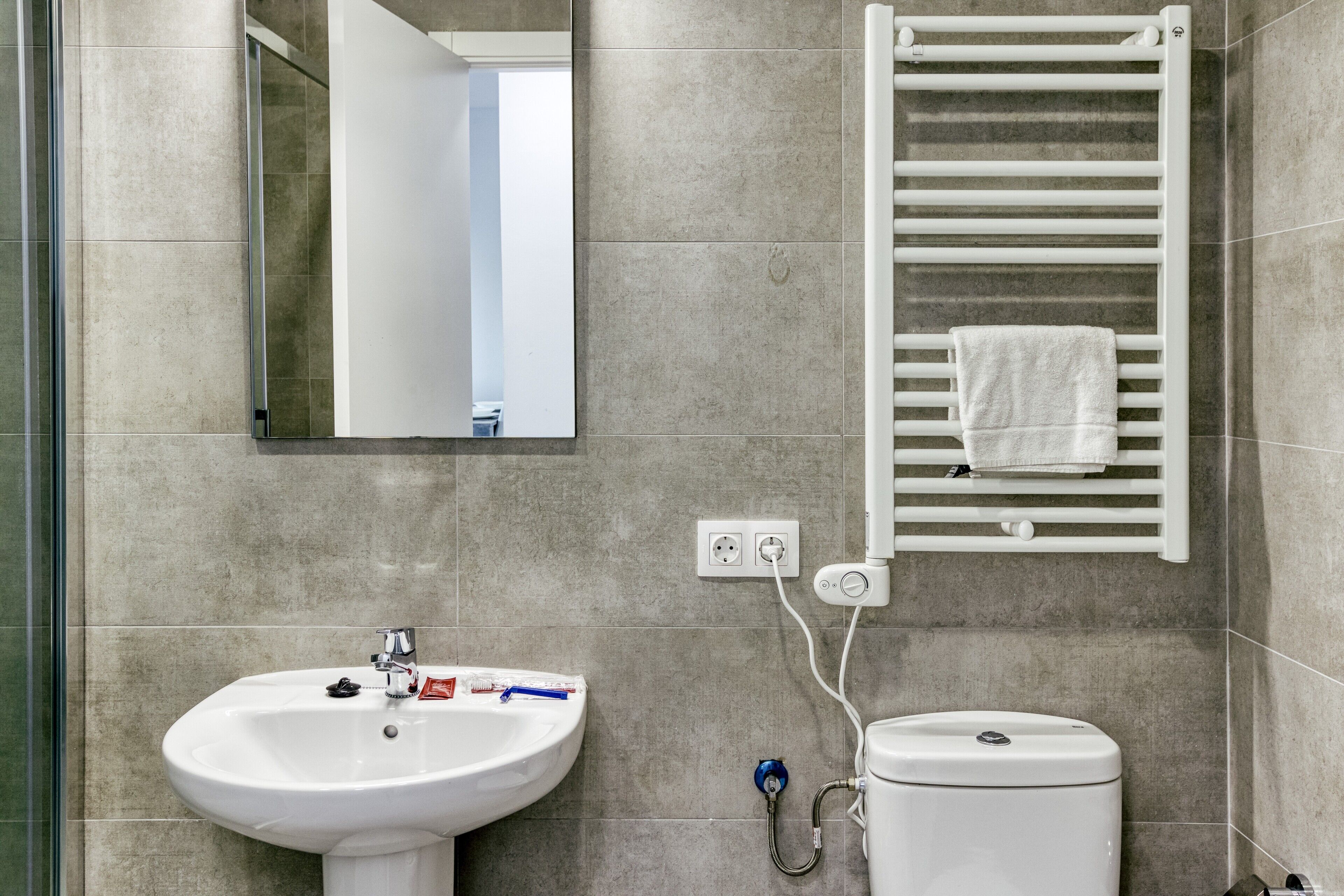 Een badkamer met een wit wastafelmeubel, spiegel, handdoekhouder en toilet.