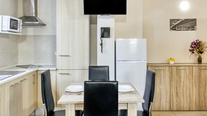 Eine moderne Küche mit Esstisch, Stühlen, Mikrowelle, Herd, Kühlschrank, Fernseher und Telefon.