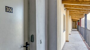 Ein Korridor mit einer Tür mit der Aufschrift '306', einem gefliesten Boden und einer Holzdeckenkonstruktion.