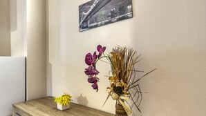 Ein Holzkabinent mit einer Blumenvase und einem kleinen Topfpflanzen darauf.