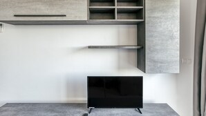 Una habitación moderna con unidad de entretenimiento empotrada, televisor de pantalla plana y alfombra gris.