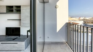 Un balcón moderno con televisor, estanterías y vista a la ciudad.