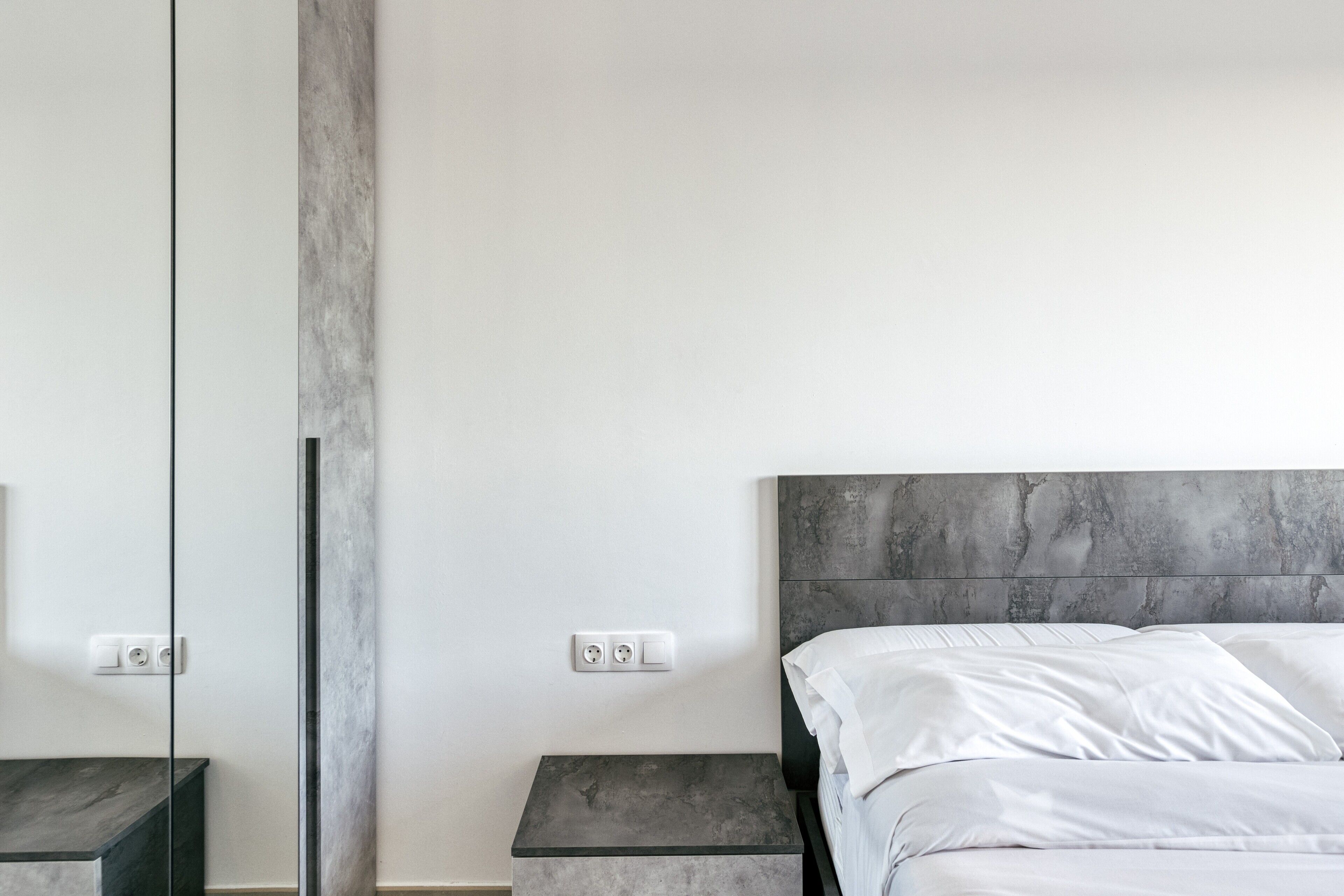 Een moderne slaapkamer met een bed, nachtkastjes en een grote spiegel.