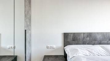 Een moderne slaapkamer met een bed, nachtkastjes en een grote spiegel.