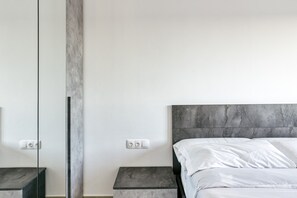 A modern bedroom with a bed, nightstands, and a large mirror.