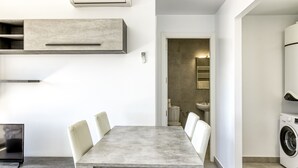 A modern kitchen with a built-in washing machine, a dining area with a table and chairs, and a visible bathroom.
