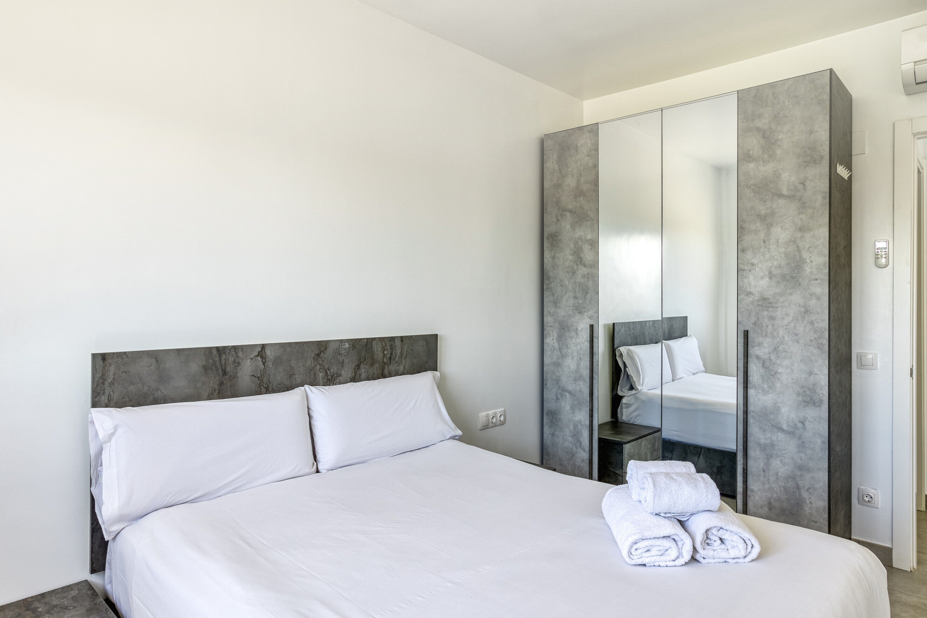 A modern hotel room with a large bed, a wardrobe, and a mirror.