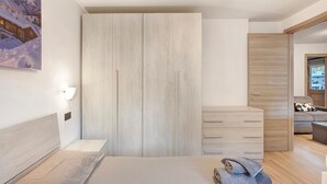A modern bedroom with a bed, a wardrobe, a dresser, and a painting on the wall. - Apartment 'Palipert Flowers House' with Mountain View, Shared Garden and Wi-Fi (Livigno)
