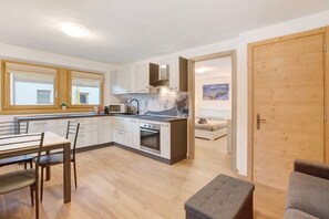 Une cuisine moderne avec des meubles en bois, un four encastré et un coin repas comprenant une table et des chaises.