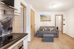Un salon moderne avec un canapé, un pouf et un tableau représentant un paysage de montagne.