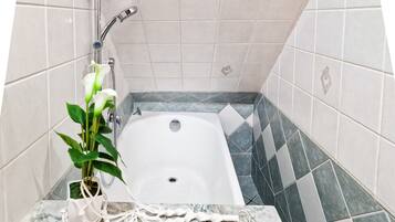 Un bagno con vasca, doccia, lavabo in marmo e una pianta in vaso.