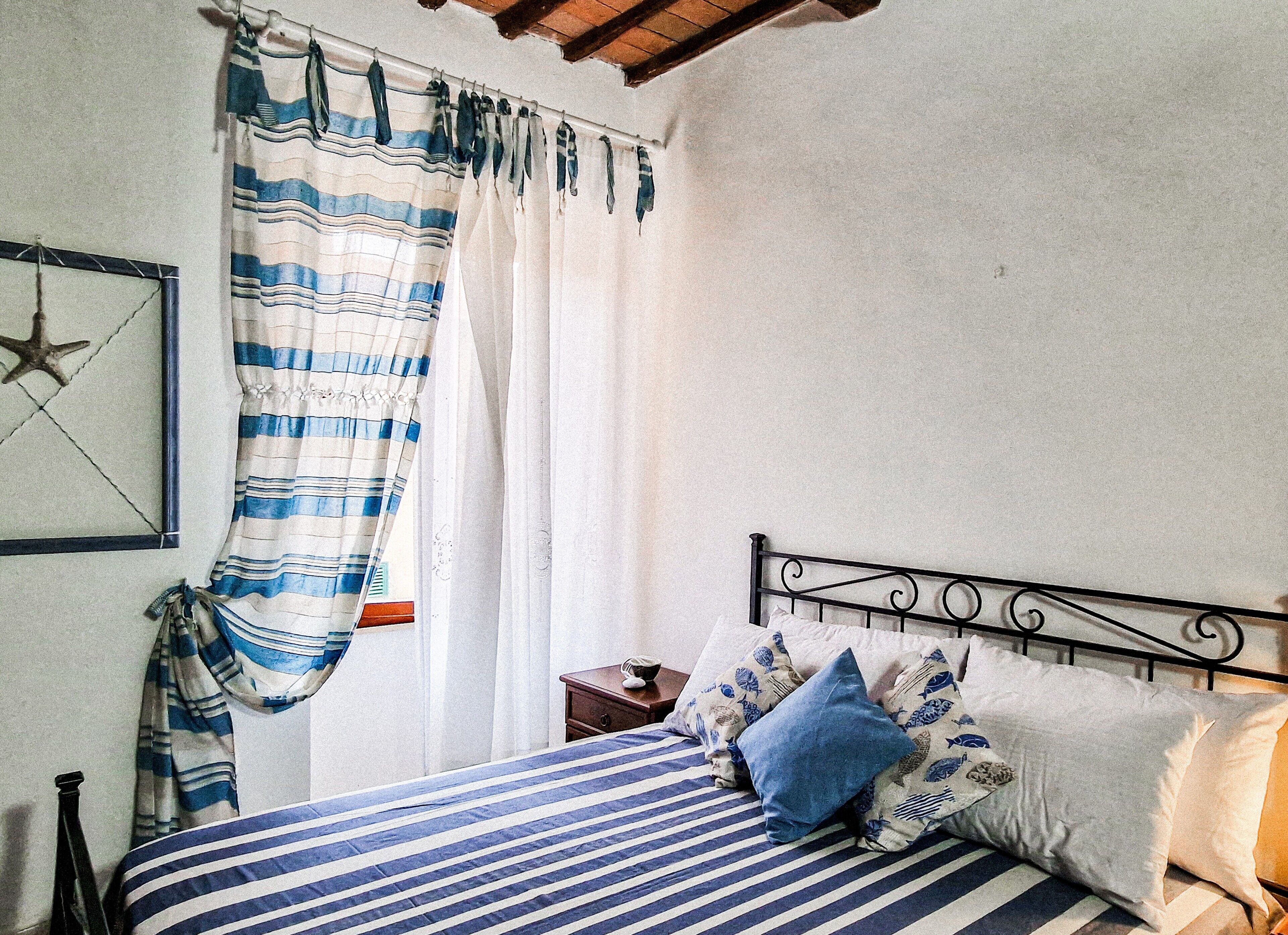 A bedroom with a bed, striped curtains, a star decoration, and a nightstand.