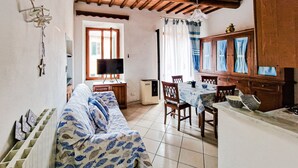 A room with a wooden ceiling, a sofa with a blue and white pattern, a dining table with chairs, a television, and a cabinet with glass doors. - Apartment 'Casa Veronica Rio Marina ' (Rio Marina)