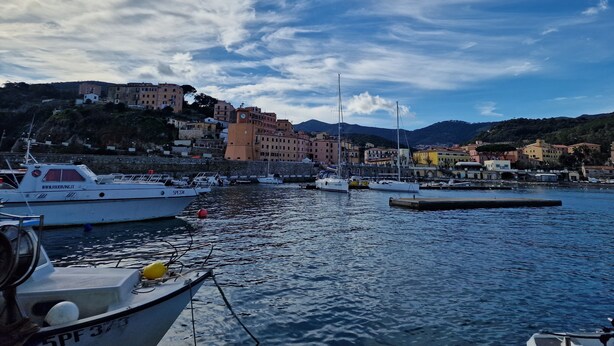 A harbor with boats docked, buildings on a hillside, and a clear sky. - Apartment 'Casa Veronica Rio Marina ' (Rio Marina)