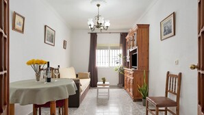A living room with a sofa, dining table, and a TV stand. - Apartment 'Ruz Bajo' for 6 people (Conil)