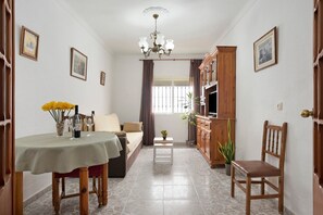 A living room with a sofa, dining table, and a TV stand.