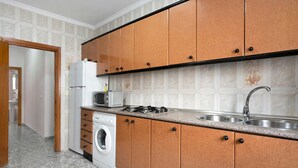 A kitchen with wooden cabinets, a washing machine, a microwave, and a sink. - Apartment 'Ruz Bajo' for 6 people (Conil)