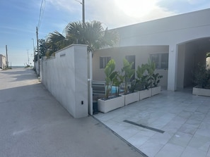 Un edificio moderno con zona de piscina, entrada protegida y cielo despejado.