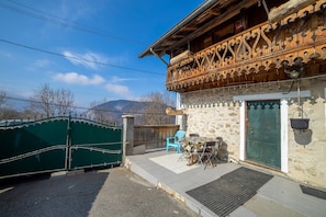 A rustic building with a balcony, a green gate, and outdoor seating. - Apartment 'Anna-Purna' with Mountain View, Shared Terrace and Wi-Fi (Arâches-la-frasse)