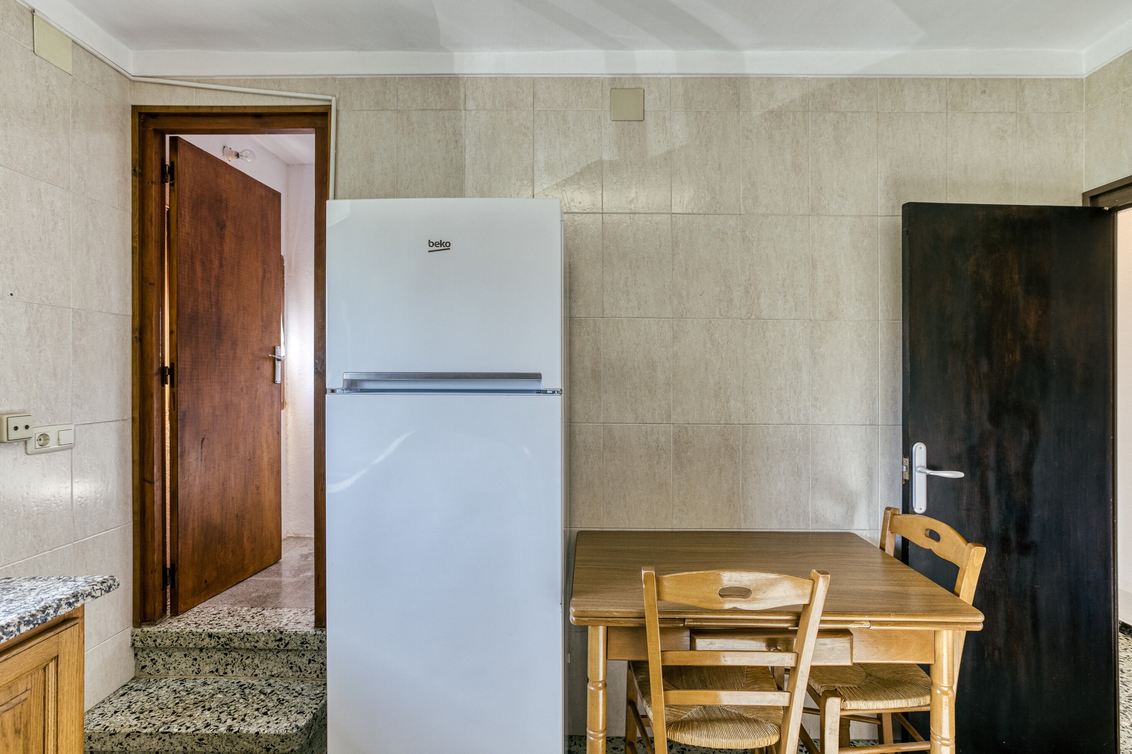 A kitchen with a white refrigerator, wooden table, and chairs.