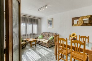 Un salon avec un canapé, des fauteuils, une table et une fenêtre avec des rideaux.