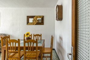 Un coin repas avec une table et des chaises en bois, un miroir fixé au mur et une horloge.