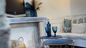 Un salon moderne doté d’un téléviseur à écran plat, d’œuvres d’art décoratives accrochées au mur, d’un canapé, d’une table basse et d’un tapis à motifs.